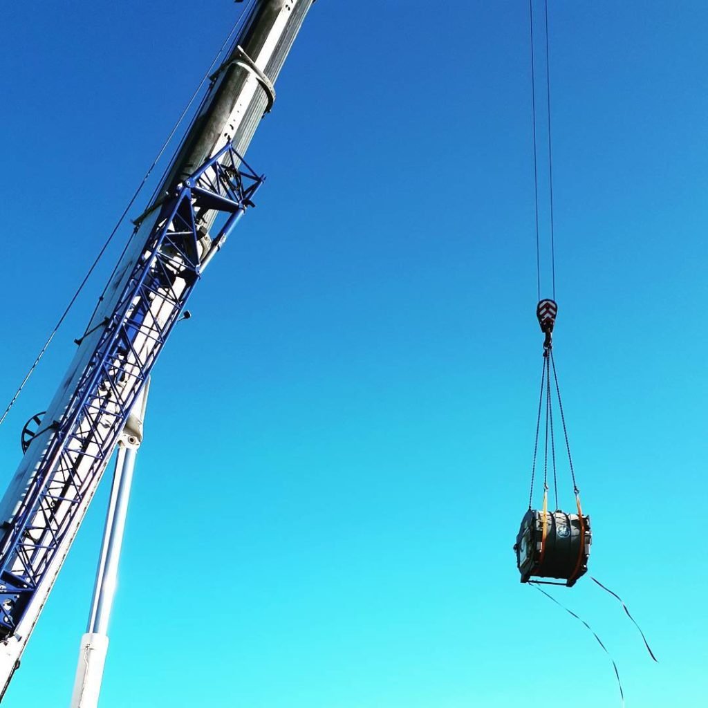 MRI scanner lifted by a 300te crane against a clear sky