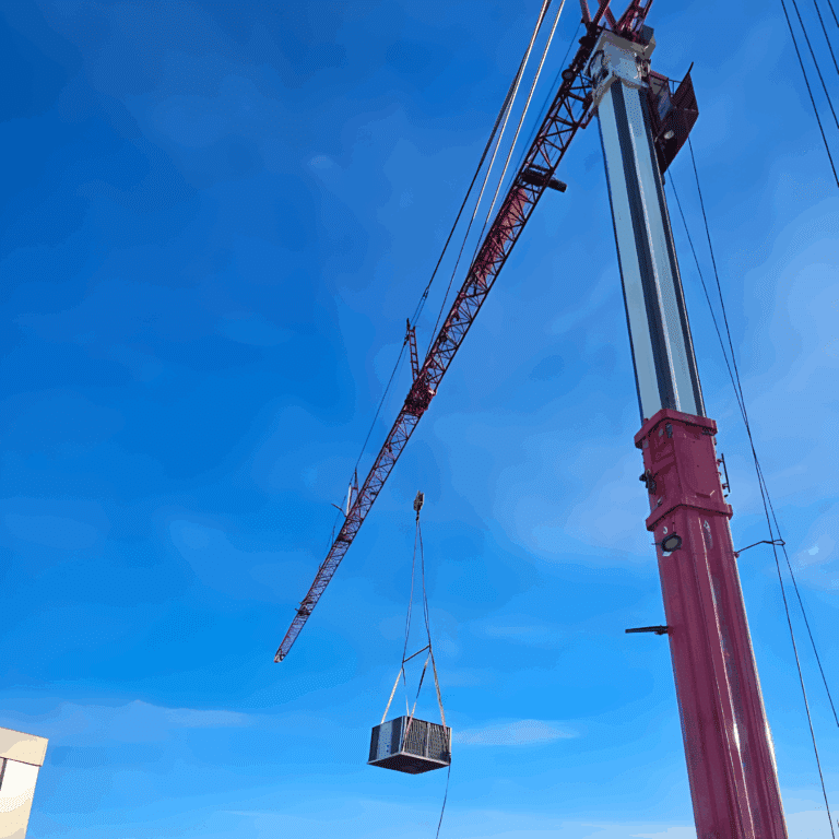 HVAC unit lifted to roof level by a mobile tower crane