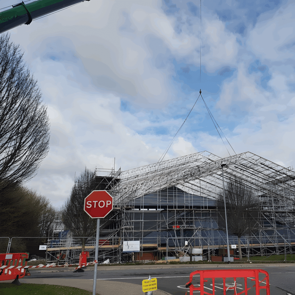Scaffolded roof section suspended from the crane above the scaffolded building