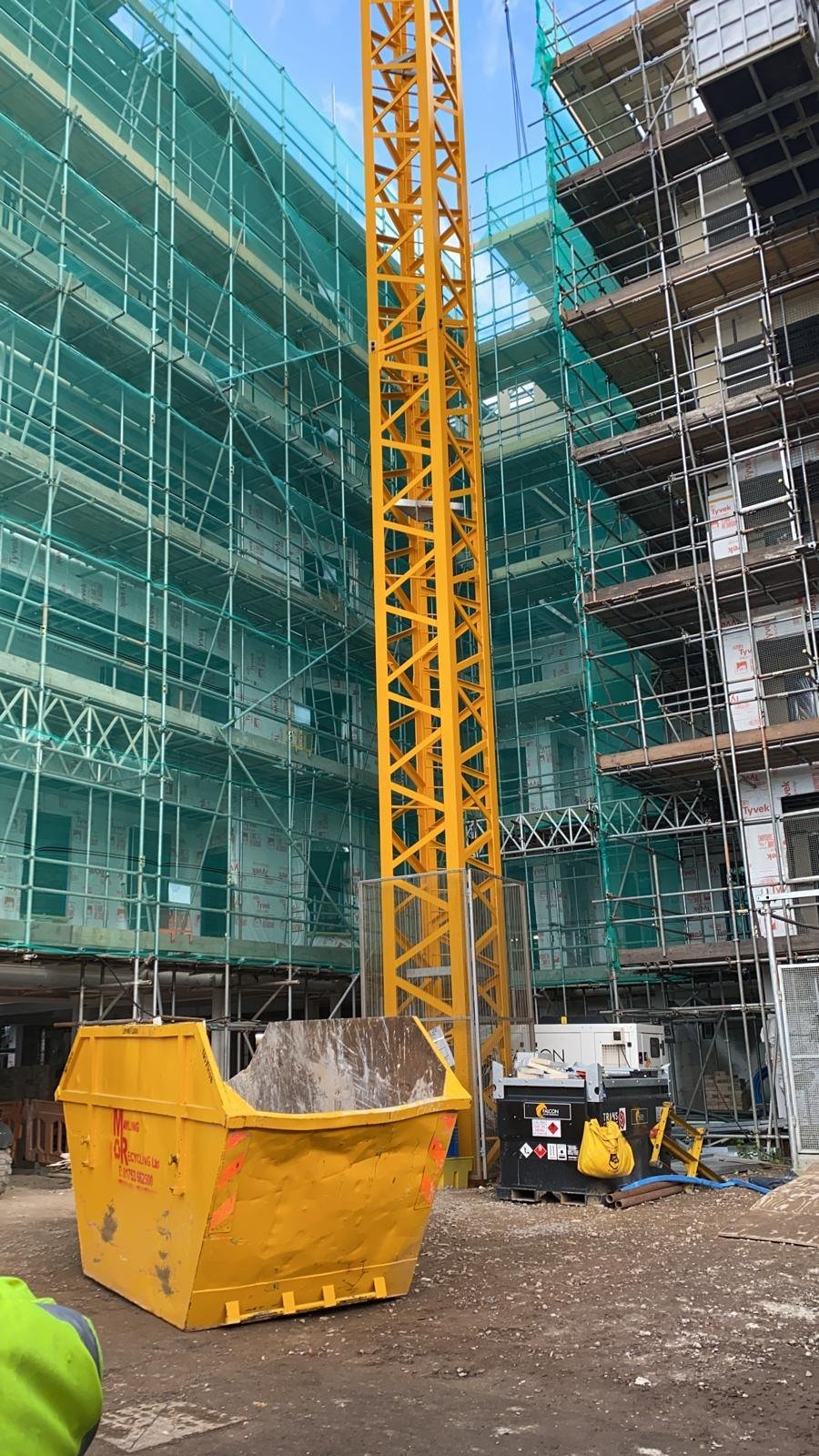 The tower crane mast running up through the middle of the scaffolded light steel frame hotel at Lampton Road, Hounslow