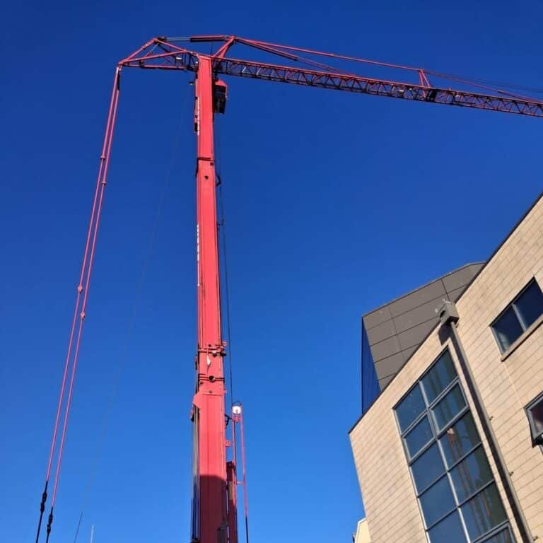 Mobile tower crane with its tower raised and jib reaching over the roof of a leisure complex in Bath for a chiller lift