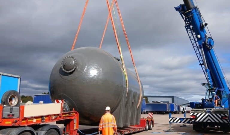 Filter vessel lifted onto a low loader in the West Midlands by a 60te all-terrain crane, with a rigger standing clear